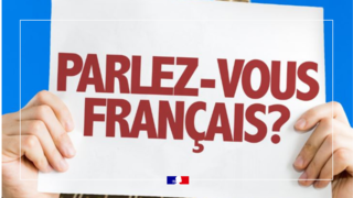 L'image représente un panneau tenu entre deux mains où il est inscrit "Parlez-vous français?"
